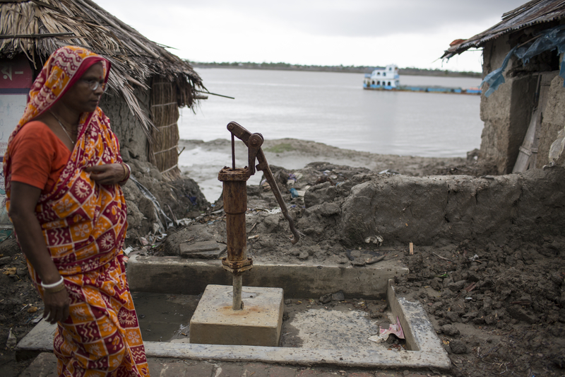 一位妇女在南孟加拉Dacope区的村庄走过。海平面上升和盐度增加正在威胁当地的生计。摄影/Conor Ashleigh